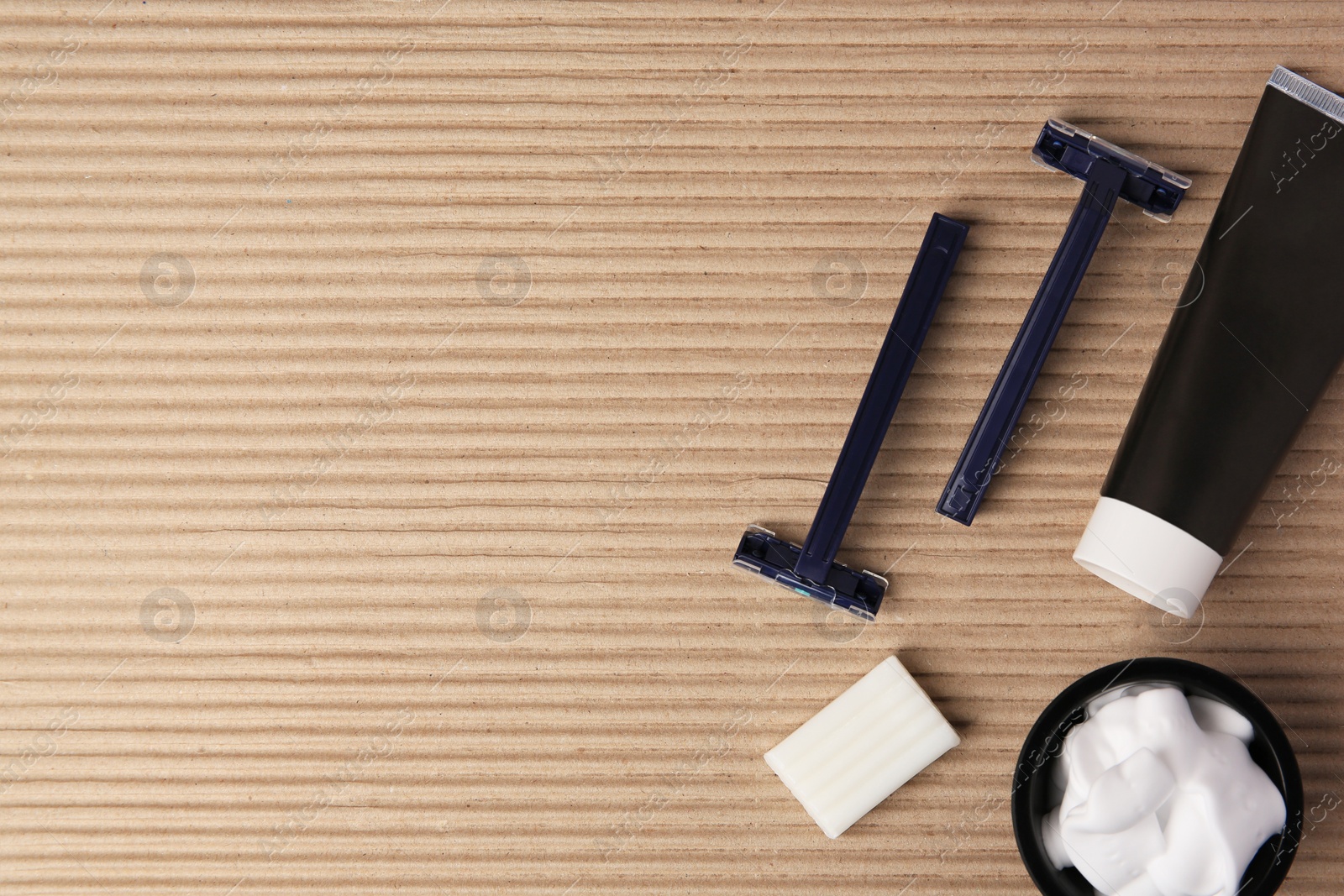 Photo of Razors, shaving foam, soap and cream on cardboard, flat lay. Space for text