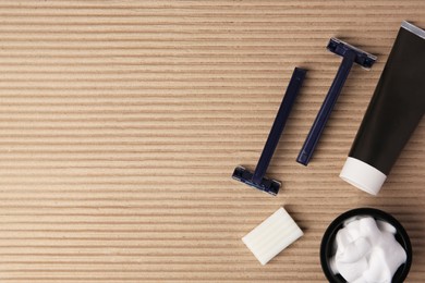 Photo of Razors, shaving foam, soap and cream on cardboard, flat lay. Space for text