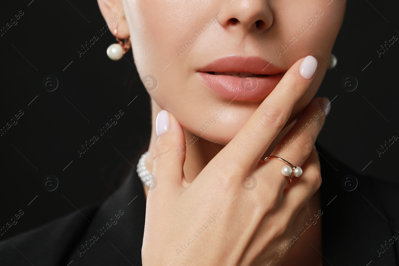 Photo of Young woman with elegant pearl jewelry on black background, closeup