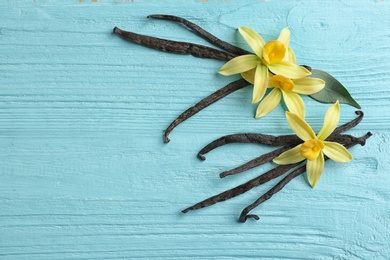 Flat lay composition with vanilla sticks and flowers on wooden background. Space for text