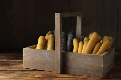 Photo of Many different raw carrots in basket on wooden table