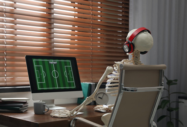 Human skeleton with headphones playing game indoors
