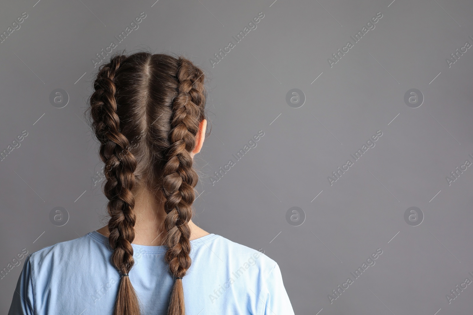 Photo of Woman with braided hair on grey background, back view. Space for text