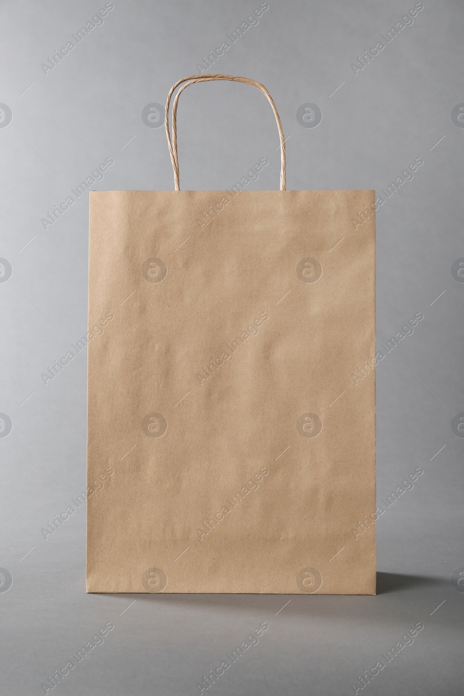 Photo of One kraft paper bag on grey background. Mockup for design