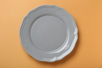 Photo of Empty ceramic plate on pale orange background, top view