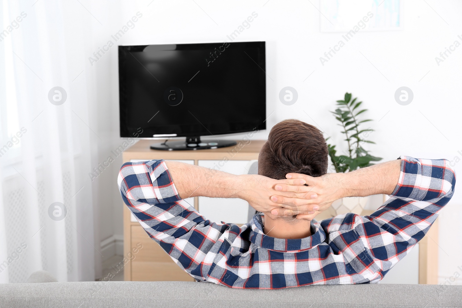 Photo of Young man watching TV on sofa at home