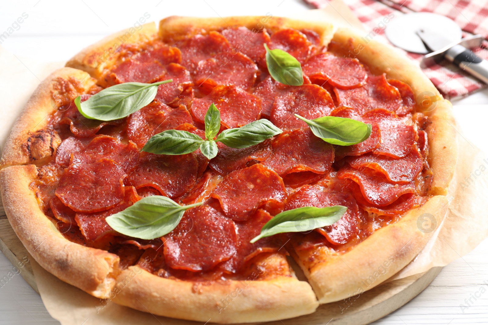 Photo of Tasty pepperoni pizza with basil on white wooden table, closeup