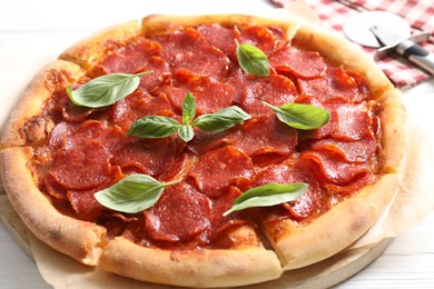 Photo of Tasty pepperoni pizza with basil on white wooden table, closeup