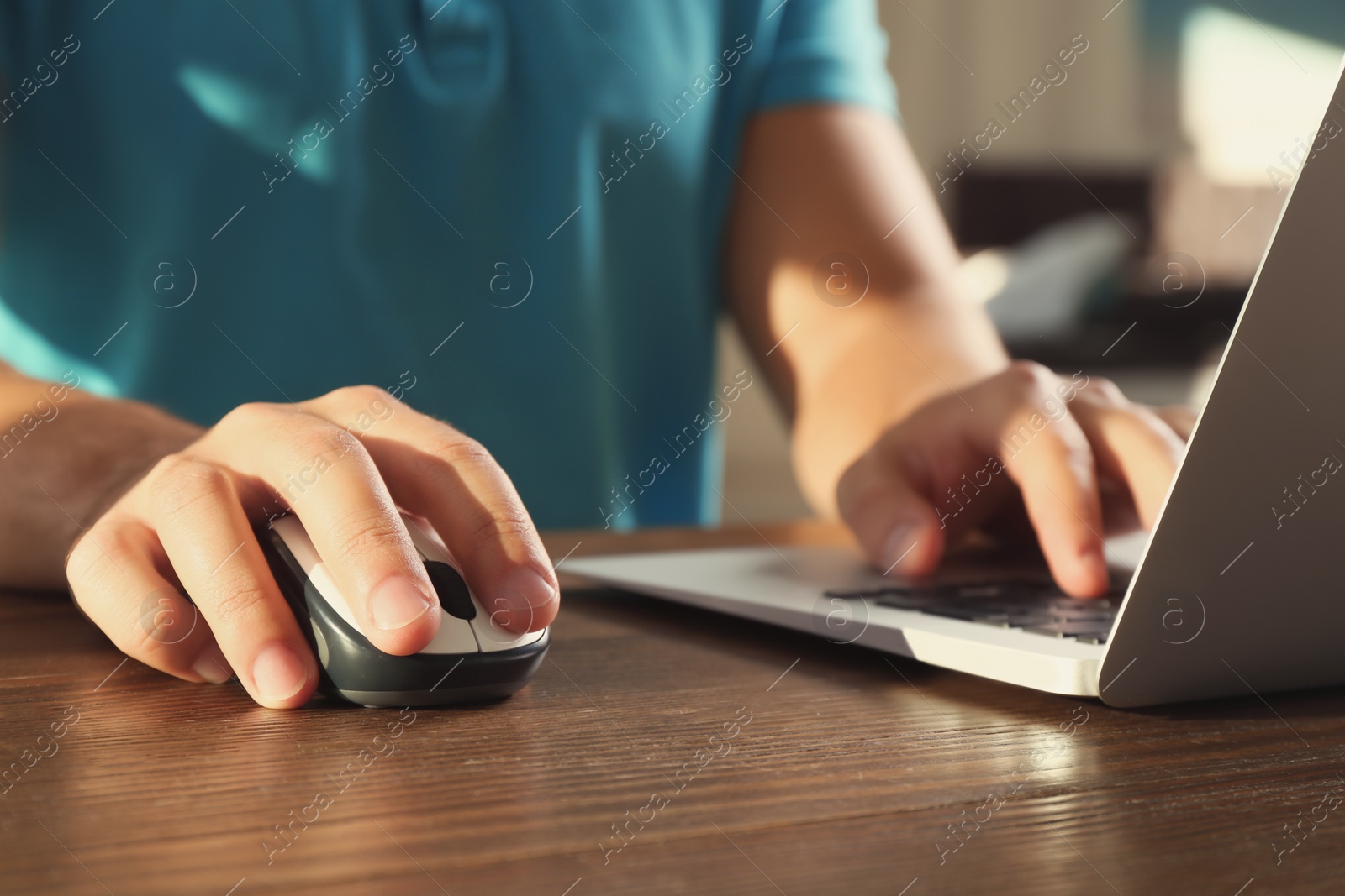 Photo of Man using computer mouse with laptop at table, closeup