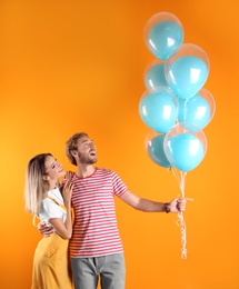 Photo of Young couple with air balloons on color background