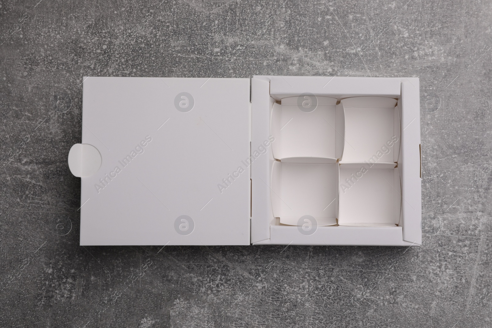 Photo of Empty white box for candies on light grey table, top view