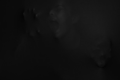 Silhouette of creepy ghost with skull behind black cloth