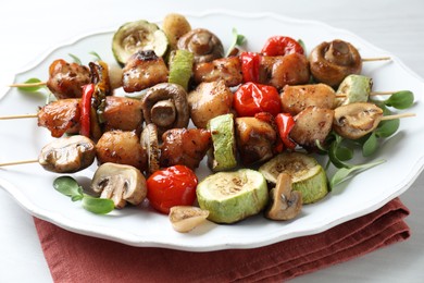 Photo of Delicious shish kebabs with vegetables and microgreens on table, closeup