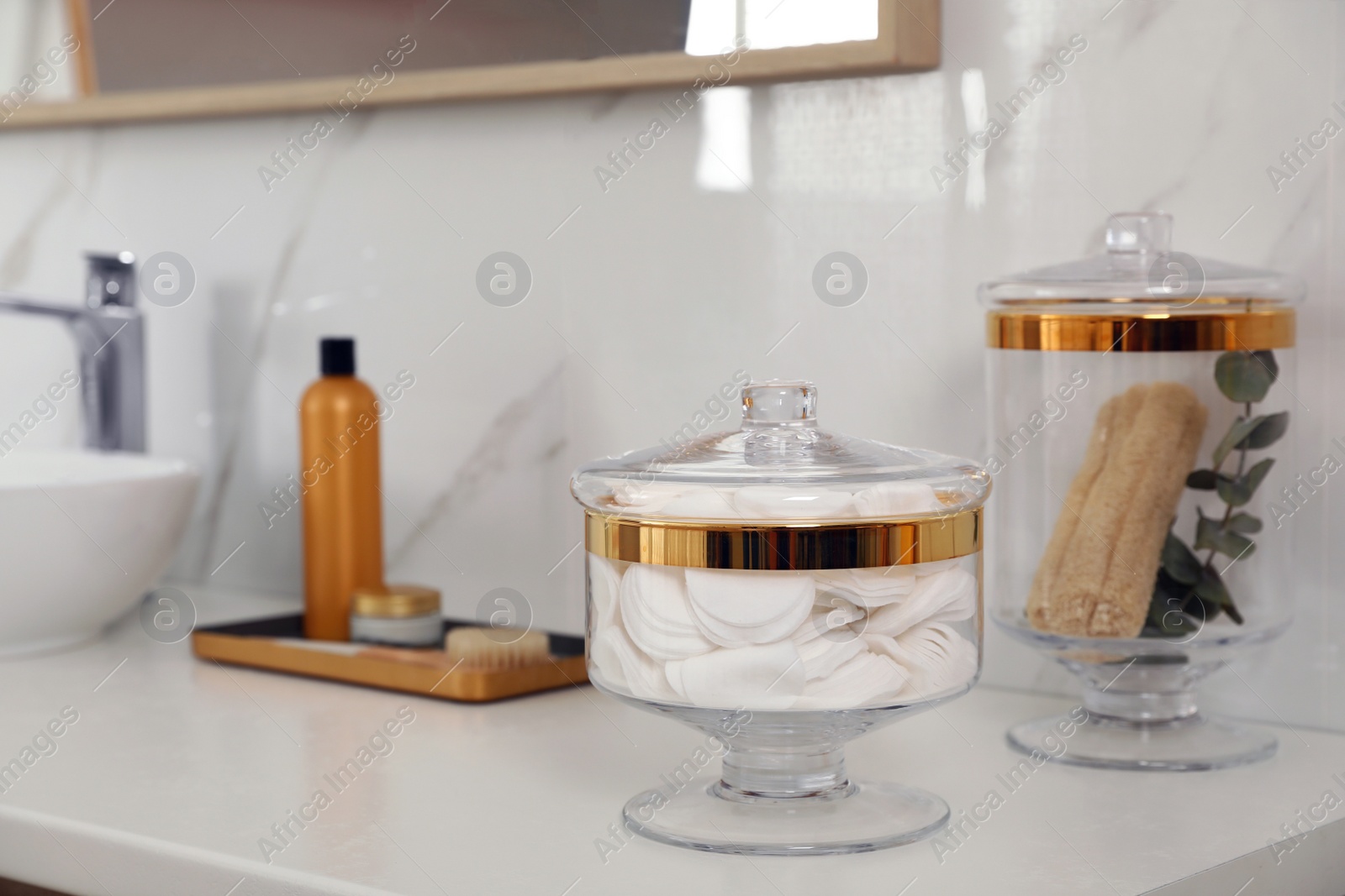 Photo of Jars with cotton pads and loofah sponges on bathroom countertop