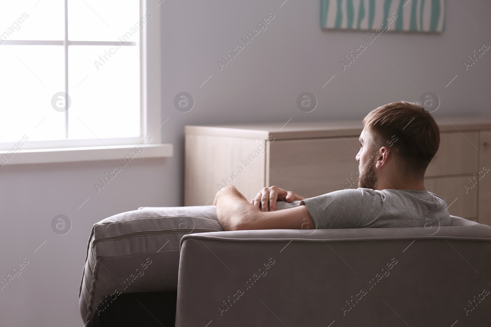 Photo of Depressed young man sitting in armchair at home