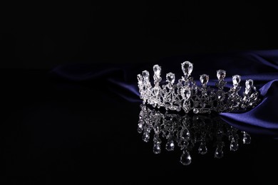 Photo of Beautiful silver tiara with diamonds on dark mirror surface. Space for text