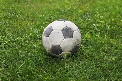 Photo of Dirty soccer ball on fresh green grass outdoors