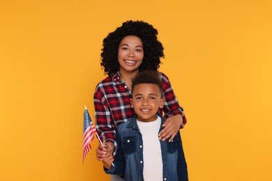 4th of July - Independence Day of USA. Happy woman and her son with American flag on yellow background