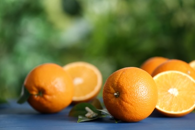 Fresh ripe oranges on blue wooden table against blurred background. Space for text