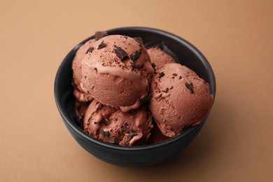 Photo of Bowl with tasty chocolate ice cream on light brown background