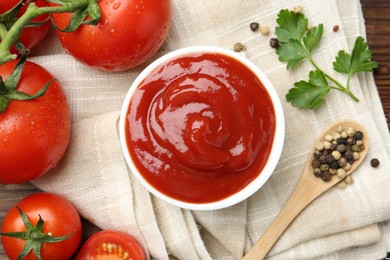 Photo of Delicious ketchup in bowl, tomatoes, parsley and peppercorns on table, top view