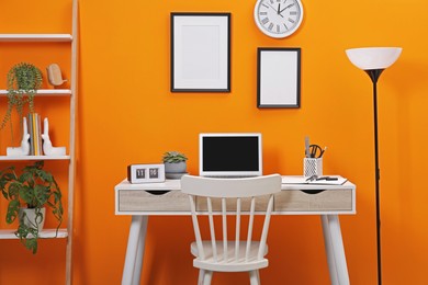 Workplace with laptop, stationery on desk and chair in home office