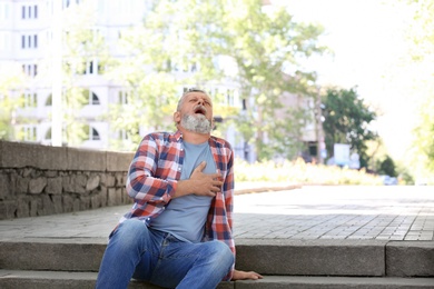 Mature man having heart attack on stairs, outdoors