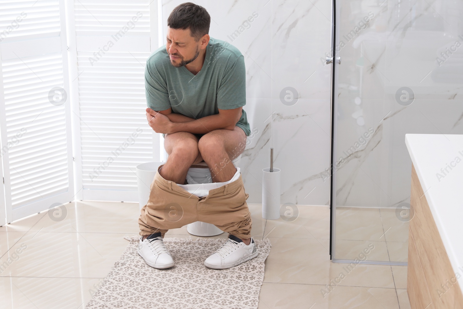 Photo of Man suffering from hemorrhoid on toilet bowl in rest room