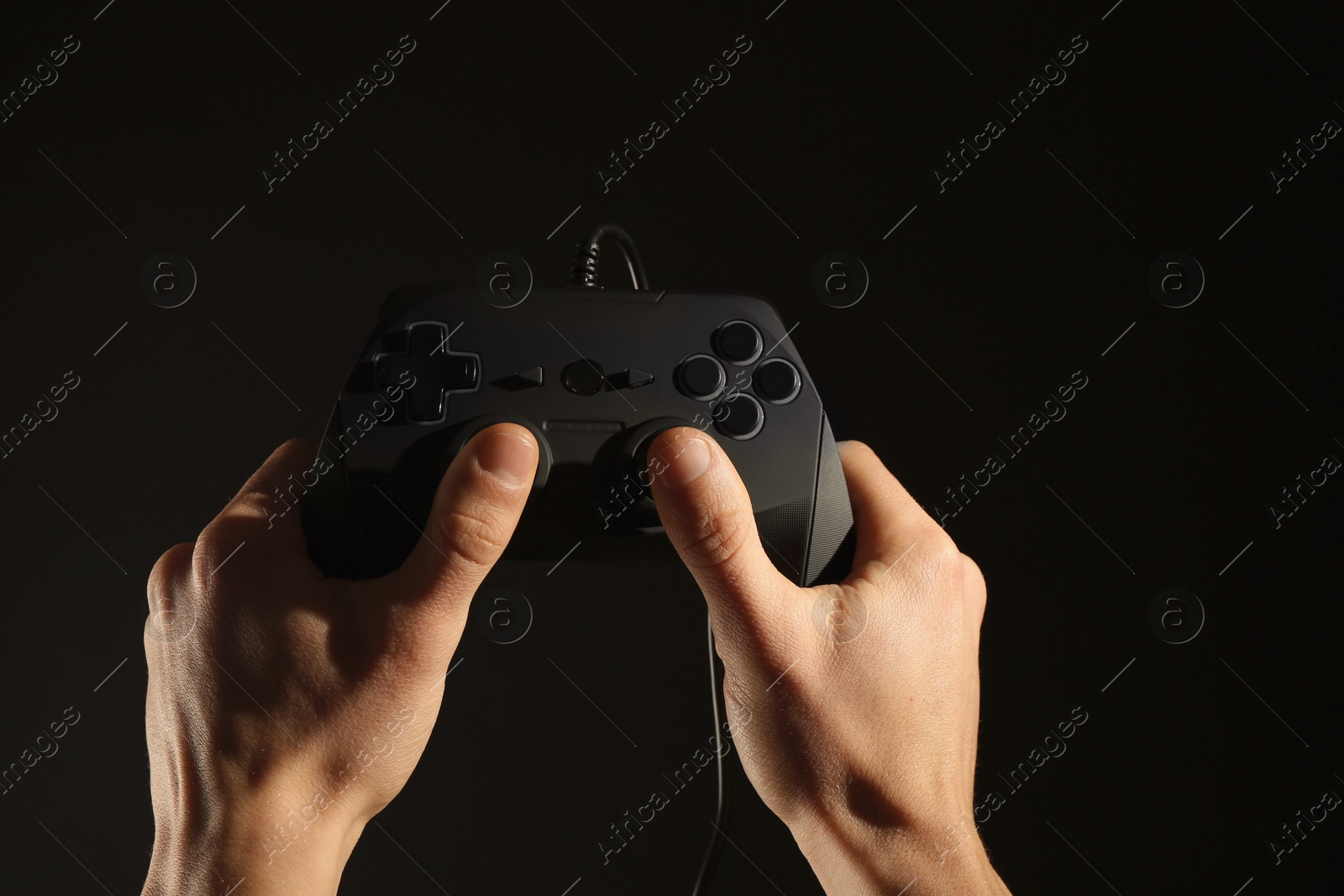 Photo of Man holding video game controller on black background, closeup