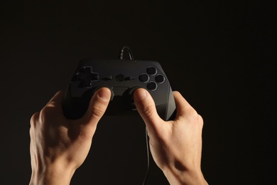 Photo of Man holding video game controller on black background, closeup