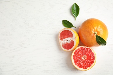 Fresh tasty grapefruits on white wooden background, top view with space for text