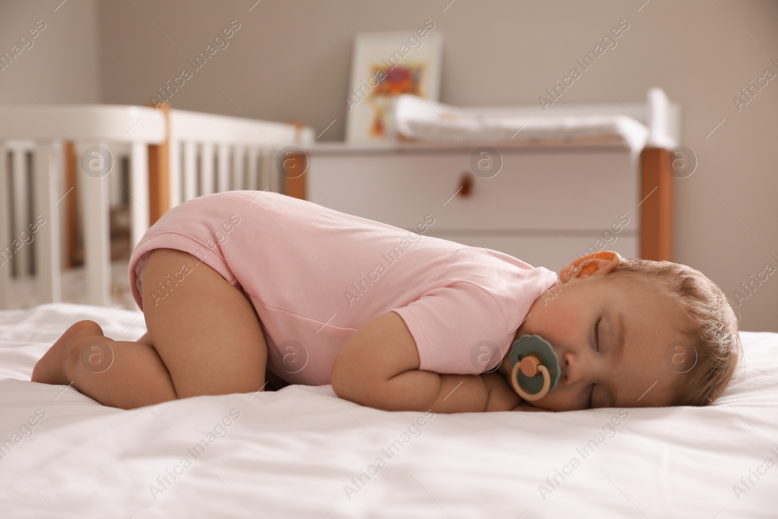 Photo of Adorable little baby with pacifier sleeping on bed at home