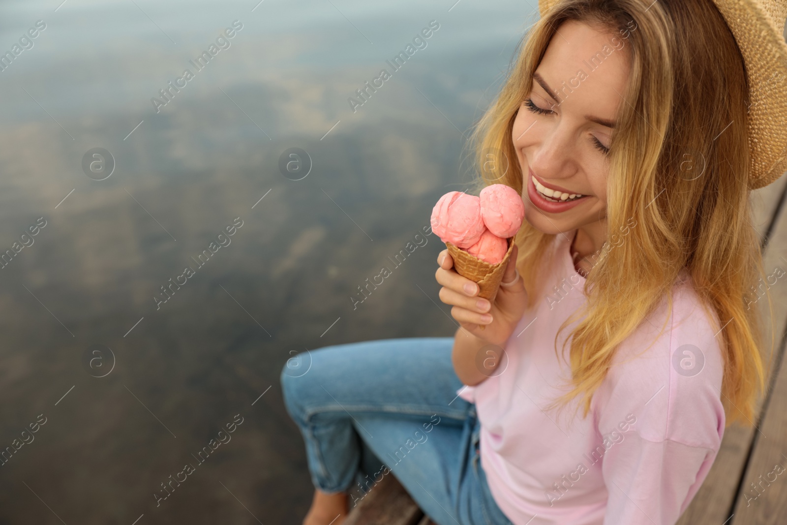 Photo of Happy young woman with delicious ice cream in waffle cone outdoors. Space for text