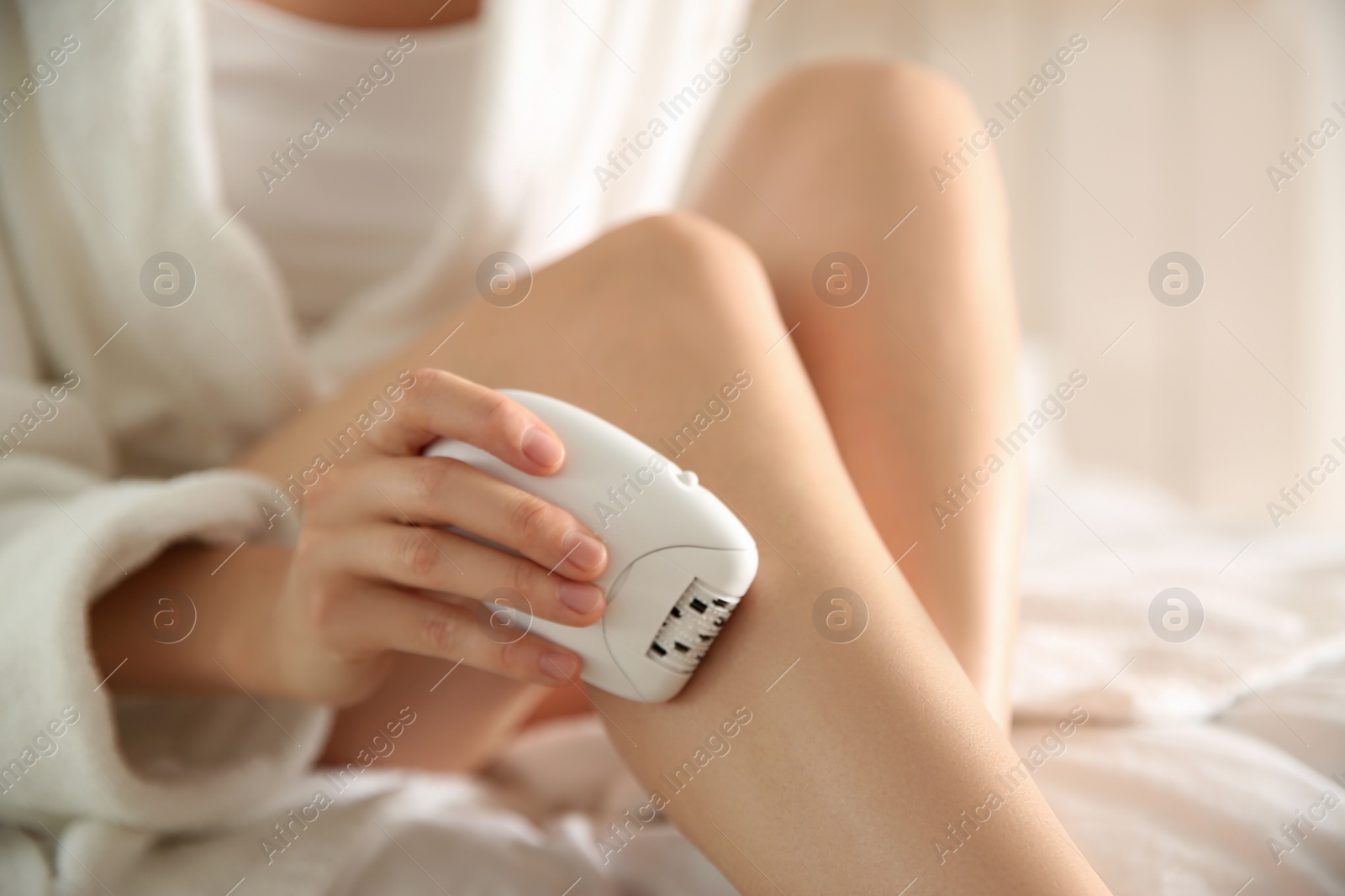 Photo of Woman doing leg epilation procedure on blurred background, closeup