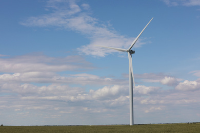 Photo of Beautiful view of field with wind turbine. Alternative energy source