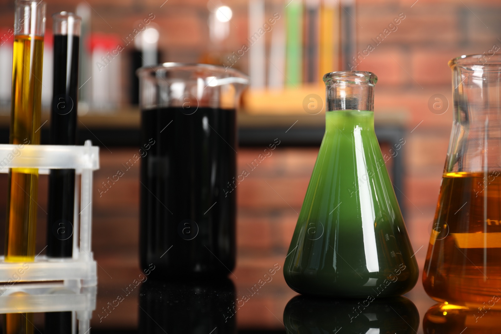 Photo of Laboratory glassware with different types of oil on mirror table indoors, closeup