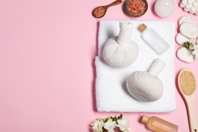 Flat lay composition with herbal massage bags and other spa products on pink background, space for text