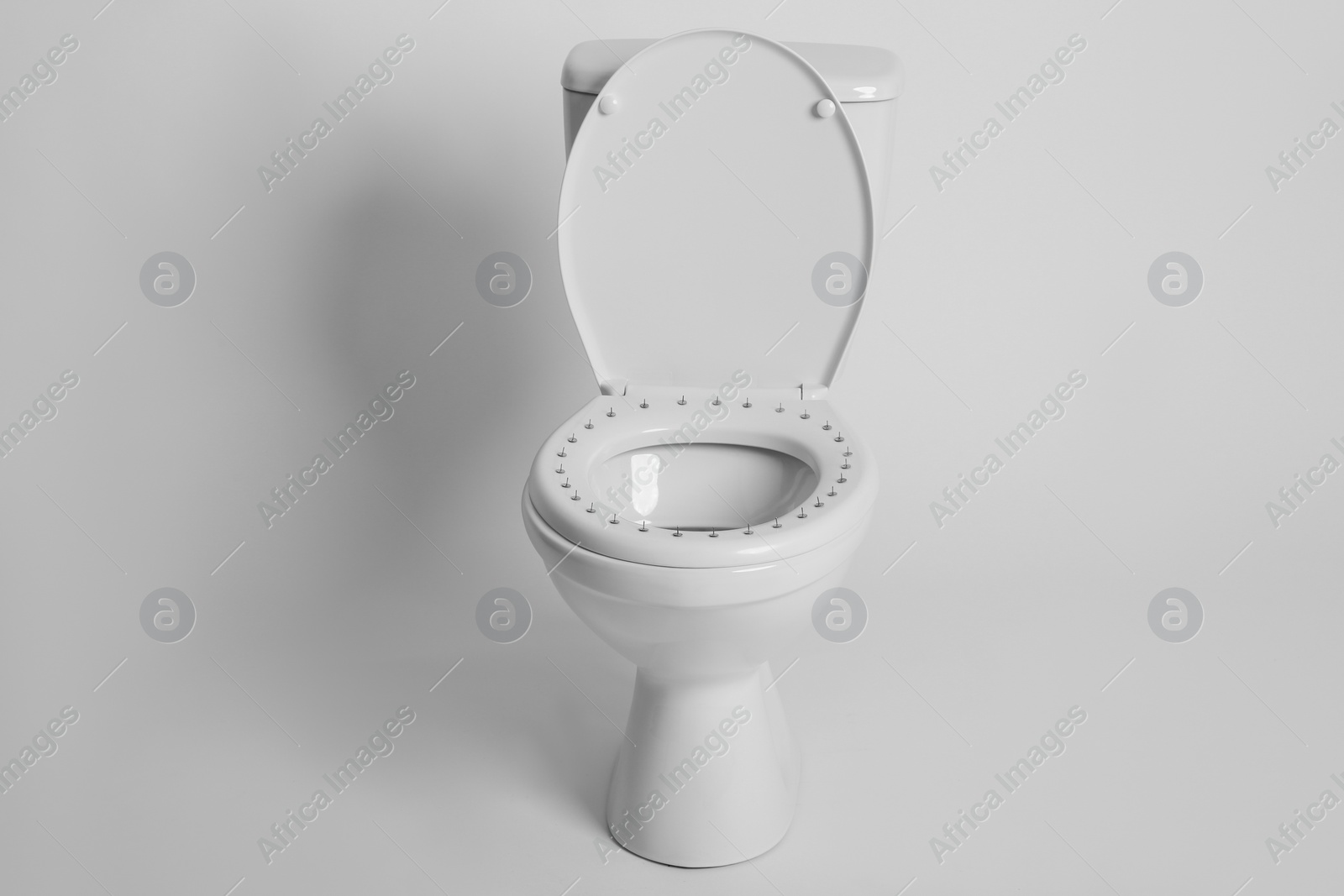 Photo of Toilet bowl with pins on white background. Hemorrhoids concept