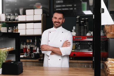 Portrait of happy baker at desk in his cafe