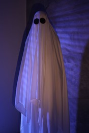 Creepy ghost. Woman covered with sheet in color lights