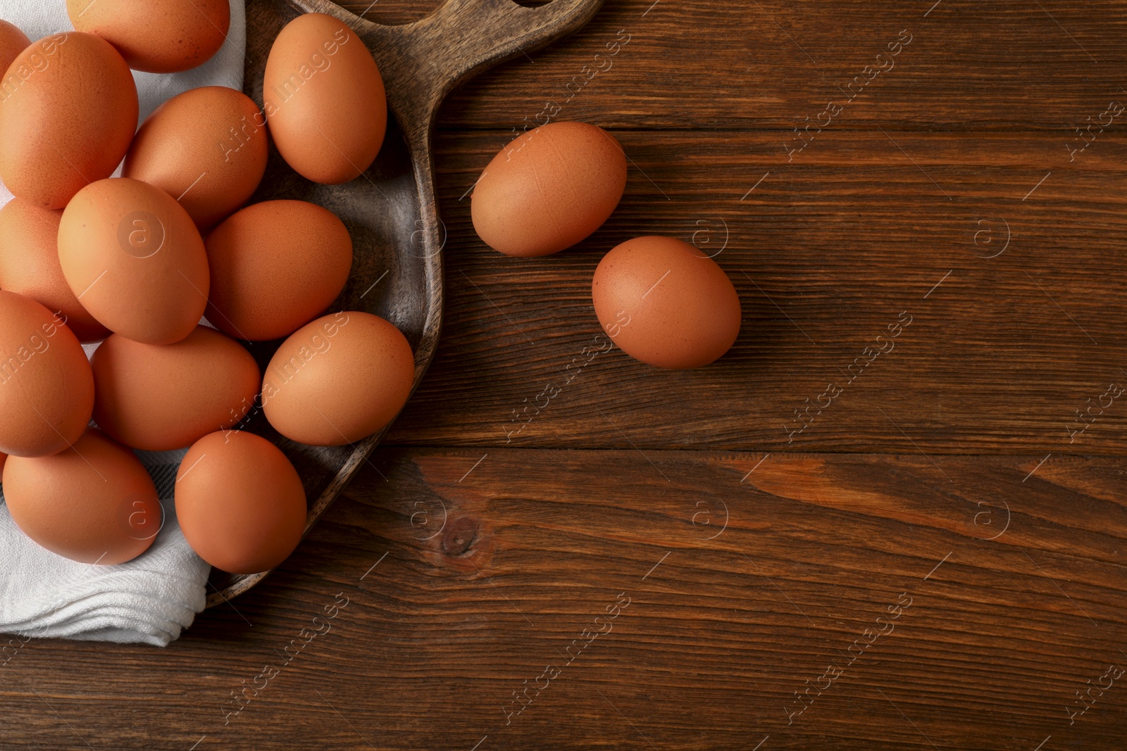 Photo of Raw brown chicken eggs on wooden table, flat lay. Space for text