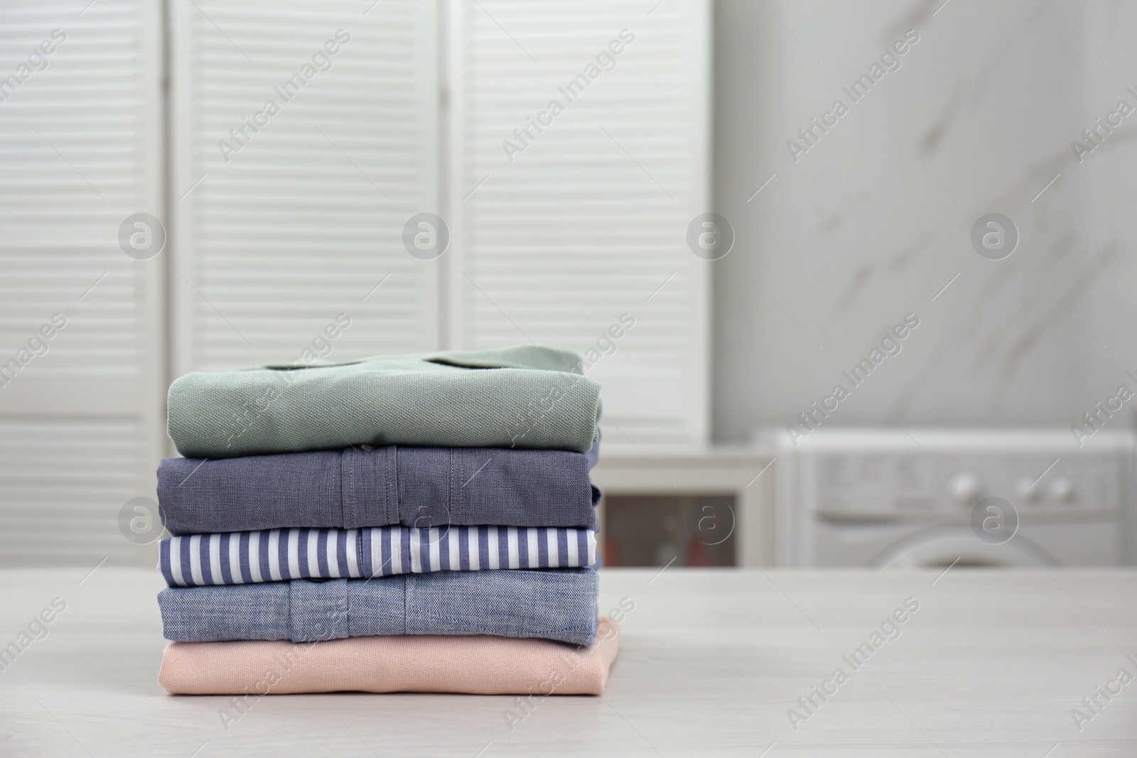 Photo of Fresh laundry on white wooden table in bathroom. Space for text