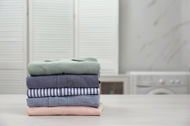 Fresh laundry on white wooden table in bathroom. Space for text