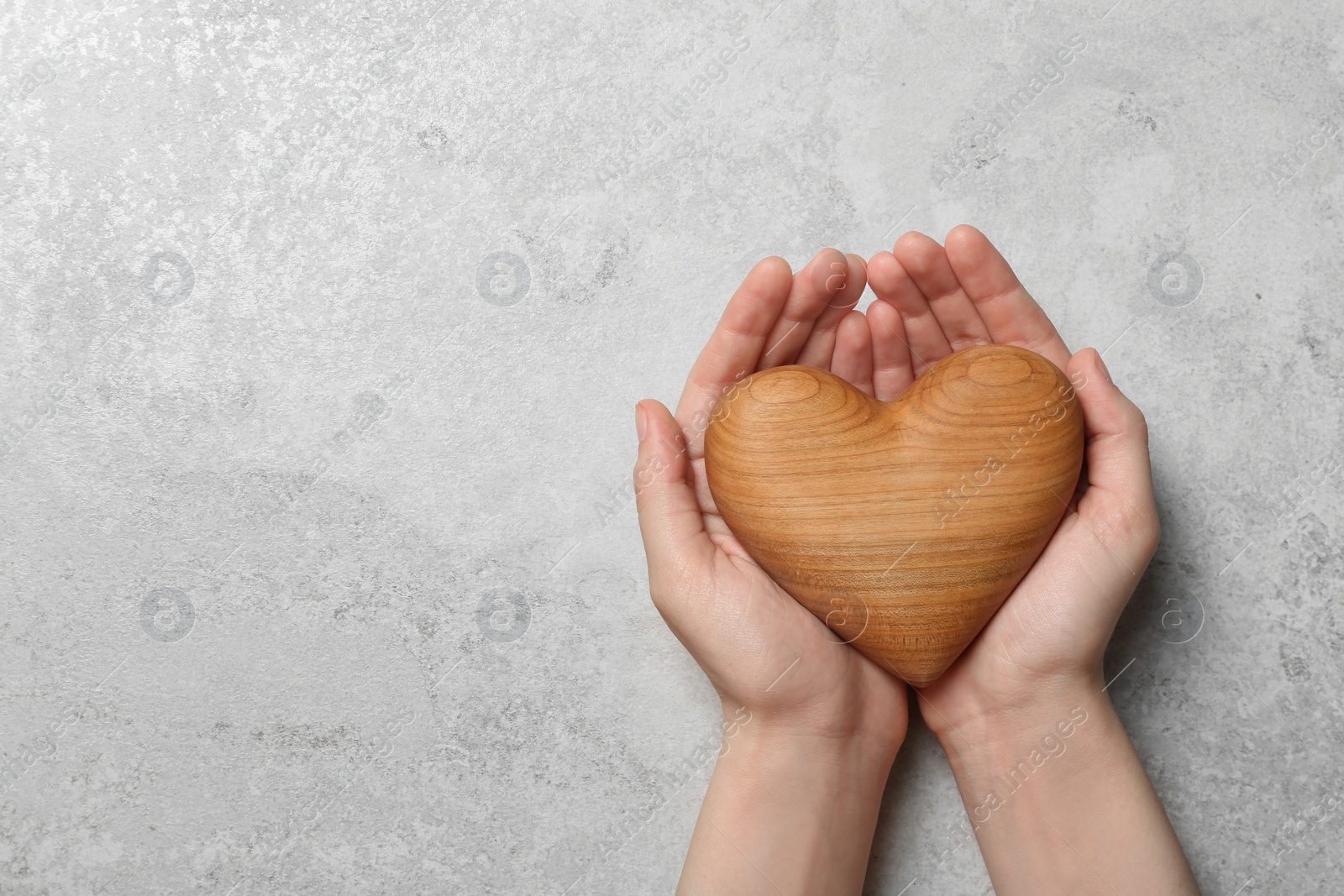 Photo of Woman holding heart on grey stone background, top view with space for text. Donation concept