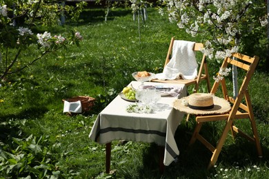 Stylish table setting with beautiful spring flowers in garden on sunny day