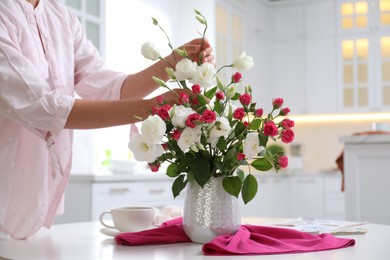 Photo of Woman with bouquetfresh flowers in stylish vase at table, closeup