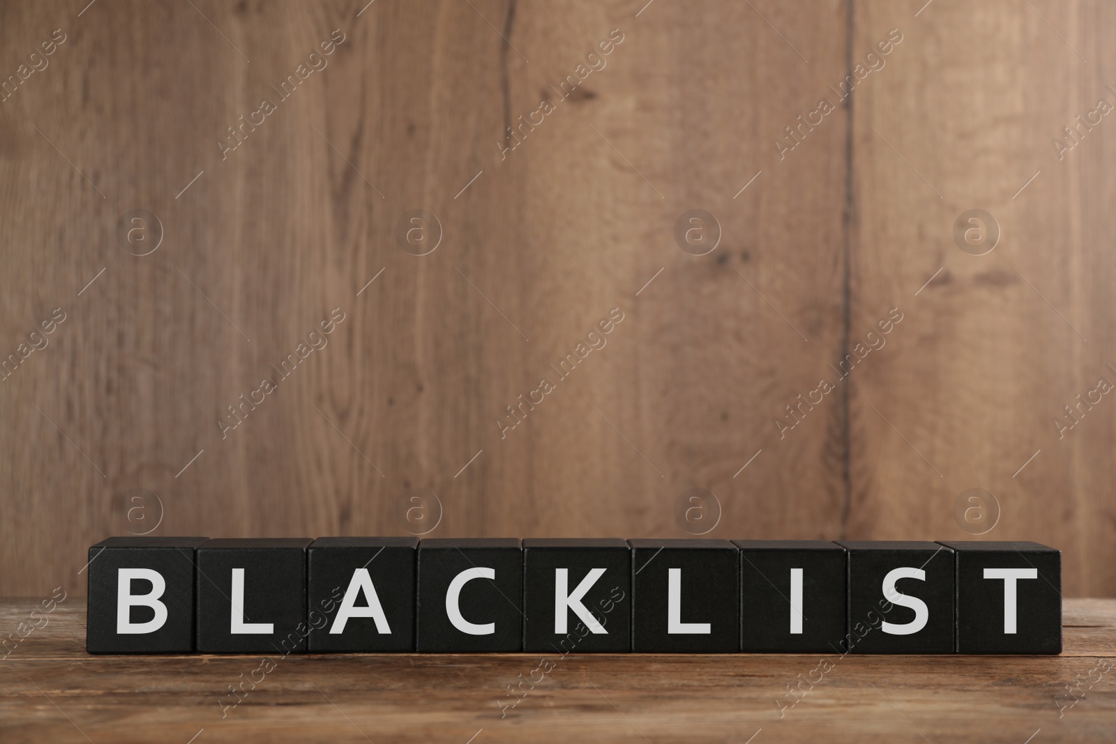 Photo of Black cubes with word Blacklist on wooden table