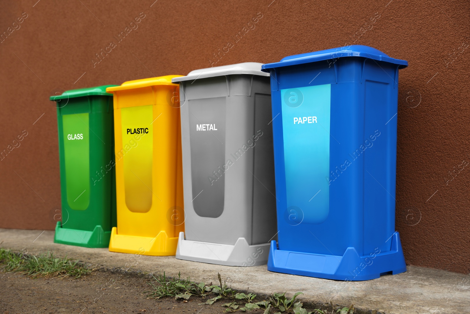 Photo of Many color recycling bins near brown wall outdoors