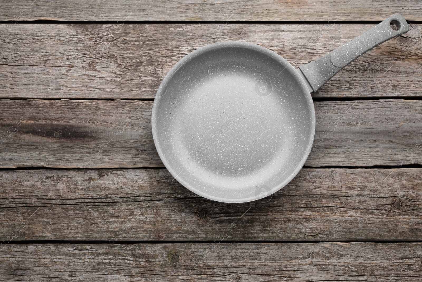 Photo of New non-stick frying pan on wooden table, top view. Space for text