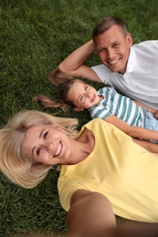 Photo of Happy family taking selfie on green grass in park